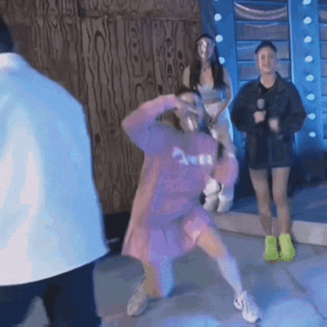 a woman in a pink dress is dancing on a stage in front of a crowd .