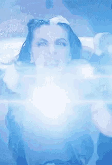 a woman is standing in a pool of water with a blue light coming out of her chest .