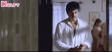 a man in a white shirt is standing in a room with a woman standing behind him .