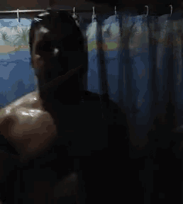 a person taking a shower in front of a blue shower curtain