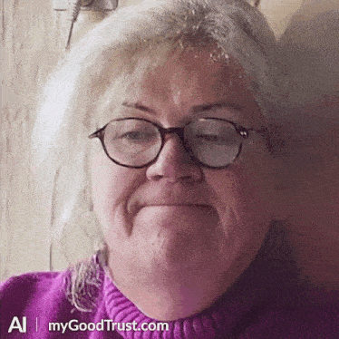 a woman wearing glasses and a purple sweater is smiling for the camera .