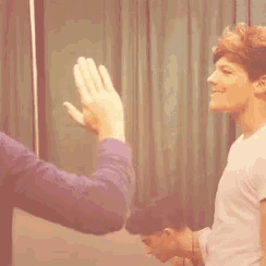 a man is giving another man a high five while another man looks on .