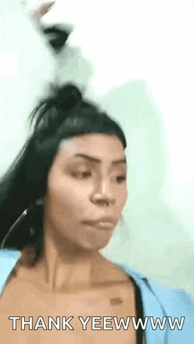 a woman in a blue shirt is making a funny face and saying `` thank yeewww '' .