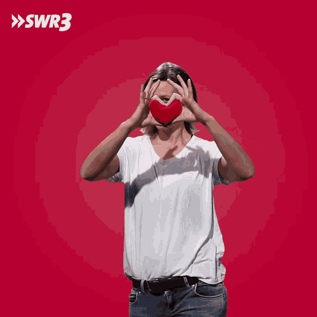 a woman making a heart shape with her hands in front of a red background with the letters swr3 on it