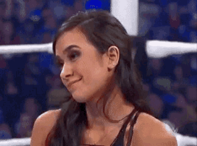 a woman is sitting in a boxing ring making a face .