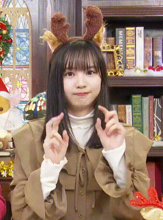 a young girl wearing a reindeer headband is making a heart shape with her hands .