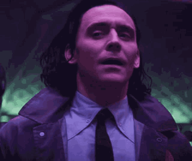 a close up of a man wearing a suit and tie in a dark room .