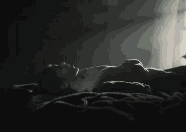 a person laying on a bed in the dark