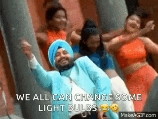 a man in a turban is dancing in front of a group of women with the caption we all can change some light bulbs .