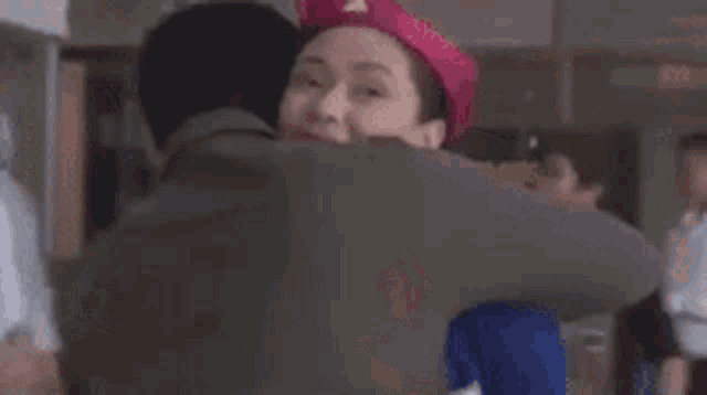 a man and a woman are hugging each other on a plane . the woman is wearing a pink hat .