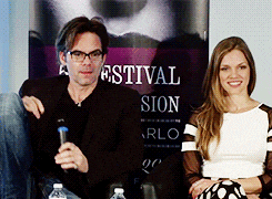 a man and a woman are sitting in front of a festival sion sign