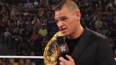 a man in a suit is holding a wrestling championship belt and says you 're in the background