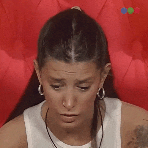 a woman wearing hoop earrings and a nose ring makes a surprised face