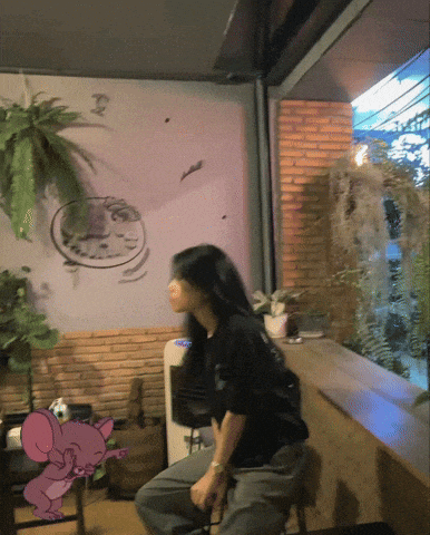 a woman sits on a stool in front of a wall with a picture of a mouse on it