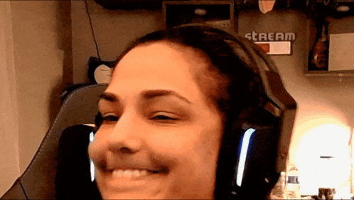 a woman wearing headphones is smiling in front of a wall that says stream