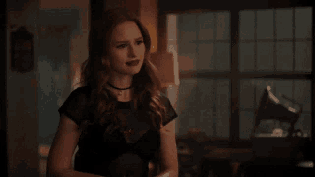 a woman in a black dress is smiling in a room .