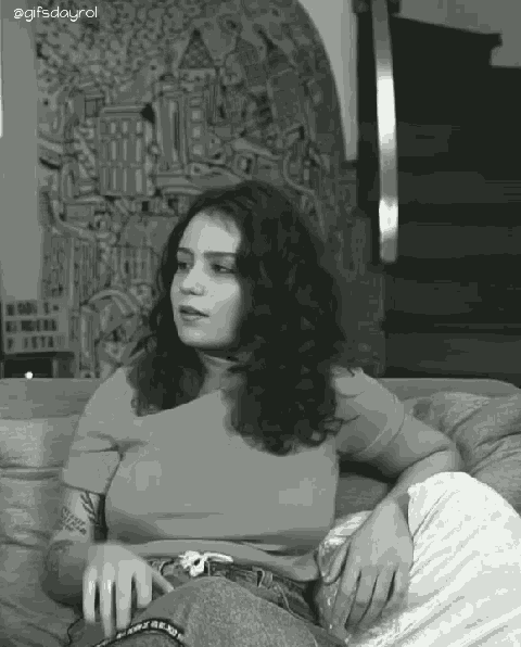 a black and white photo of a woman sitting on a couch with a gifsdayrol watermark