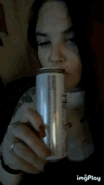 a woman is drinking from a can with a straw .