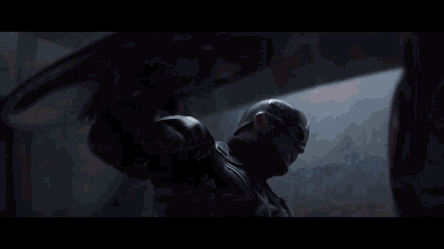 a close up of captain america 's shield and iron man 's helmet in a dark room