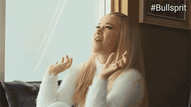 a woman is sitting on a couch with her hands in the air and the hashtag #bullsprit is above her