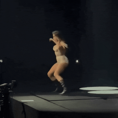 a woman is dancing on a stage with a microphone in her hand