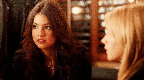 two women are sitting next to each other in a restaurant and talking .