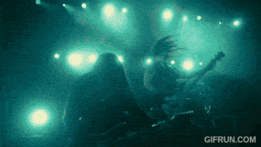 a man playing a guitar on a stage with the website gifrun.com visible in the corner