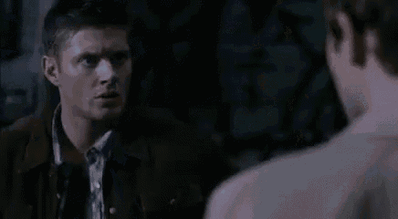 a man in a brown jacket is talking to another man in a white shirt .