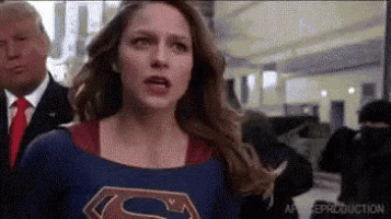 a woman dressed as superman is standing in front of a man in a suit and tie .