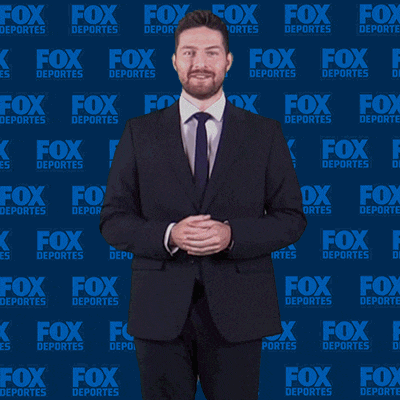 a man in a suit and tie stands in front of a fox deportes background