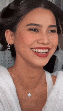 a close up of a woman 's face with a necklace and earrings