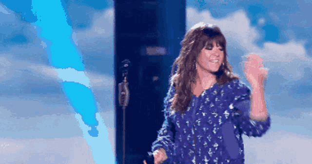 a woman in a blue shirt is dancing on a stage