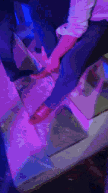 a man in a white shirt sits on a couch in a dark room with blue lights behind him