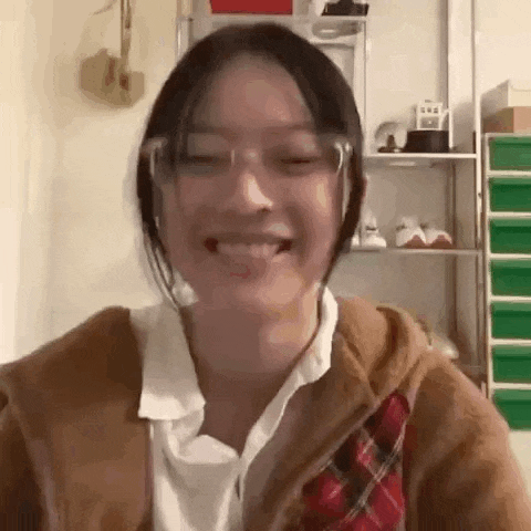 a woman wearing glasses and a plaid shirt is smiling and looking at the camera .