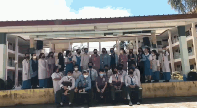 a group of people are posing for a picture in front of a building