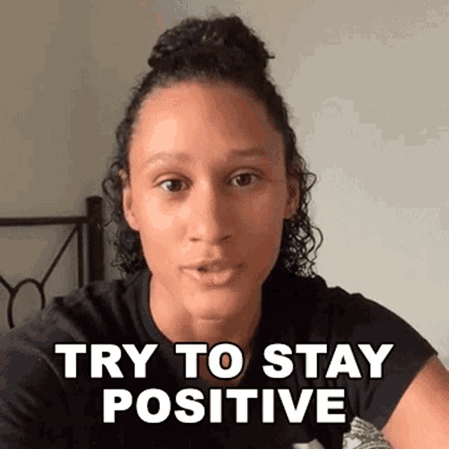 a woman with curly hair is making a funny face and says try to stay positive .