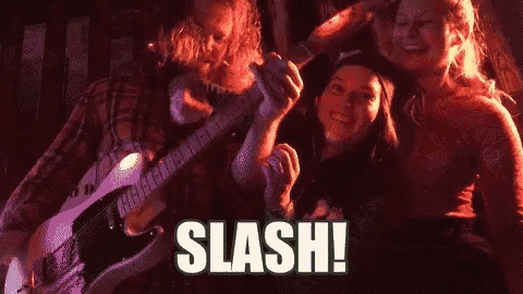 a man is playing a guitar in front of a group of people and the word slash is on the bottom of the screen .