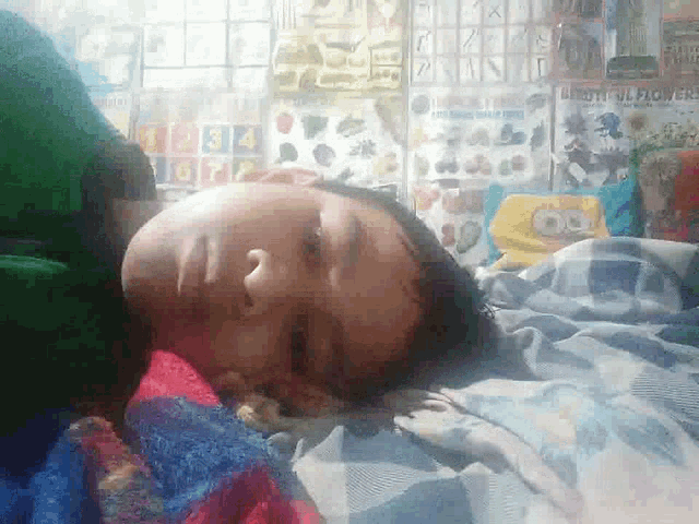 a child laying on a bed with a spongebob blanket on the floor