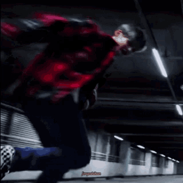 a man in a red plaid shirt is skateboarding in a parking garage .