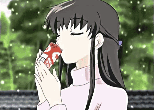 a girl in a pink sweater drinking from a red can