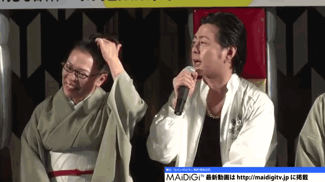 a man is holding a microphone while a woman adjusts her hair