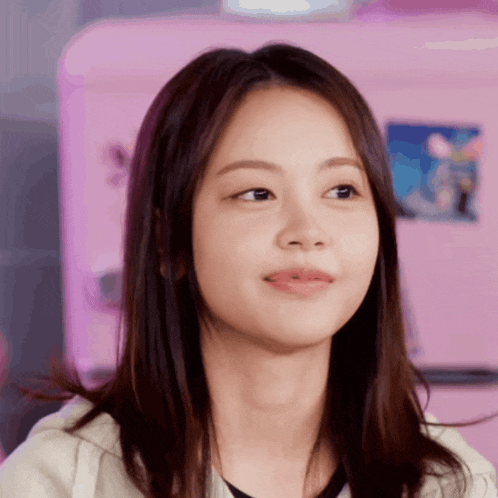 a close up of a young woman 's face with a pink refrigerator in the background