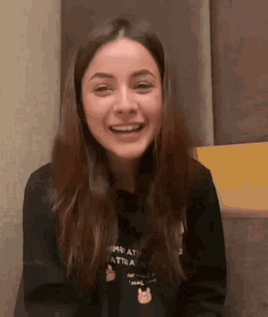a woman in a black sweatshirt is smiling and laughing .