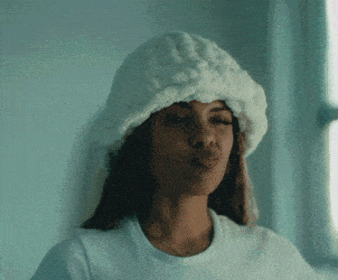 a woman wearing a white hat is blowing a kiss .