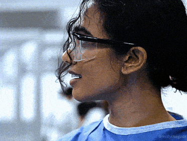 a close up of a woman wearing glasses and a blue shirt that says millythegoat