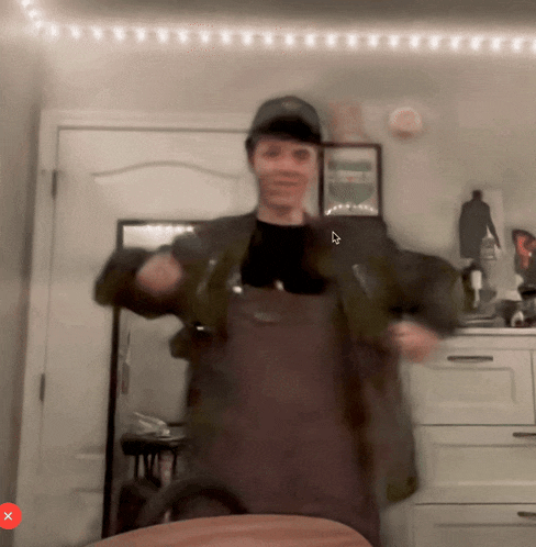 a blurry picture of a man in an apron with a x on the bottom right