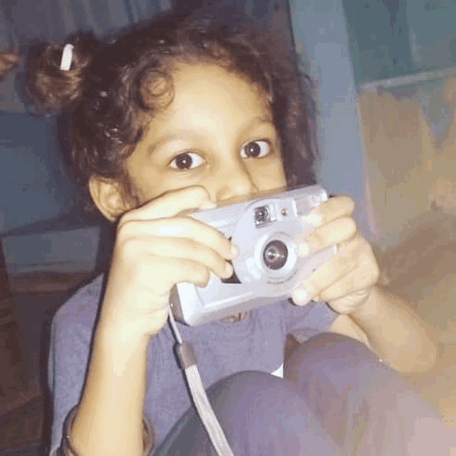 a little girl is taking a picture with a kodak camera