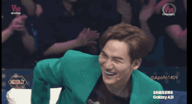a man in a green suit is laughing in front of a samsung galaxy a31 advertisement