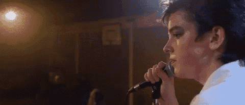 a man is singing into a microphone while wearing makeup .