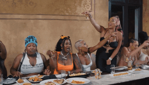 a group of women sitting at a table with one wearing a shirt that says " tequila " on it
